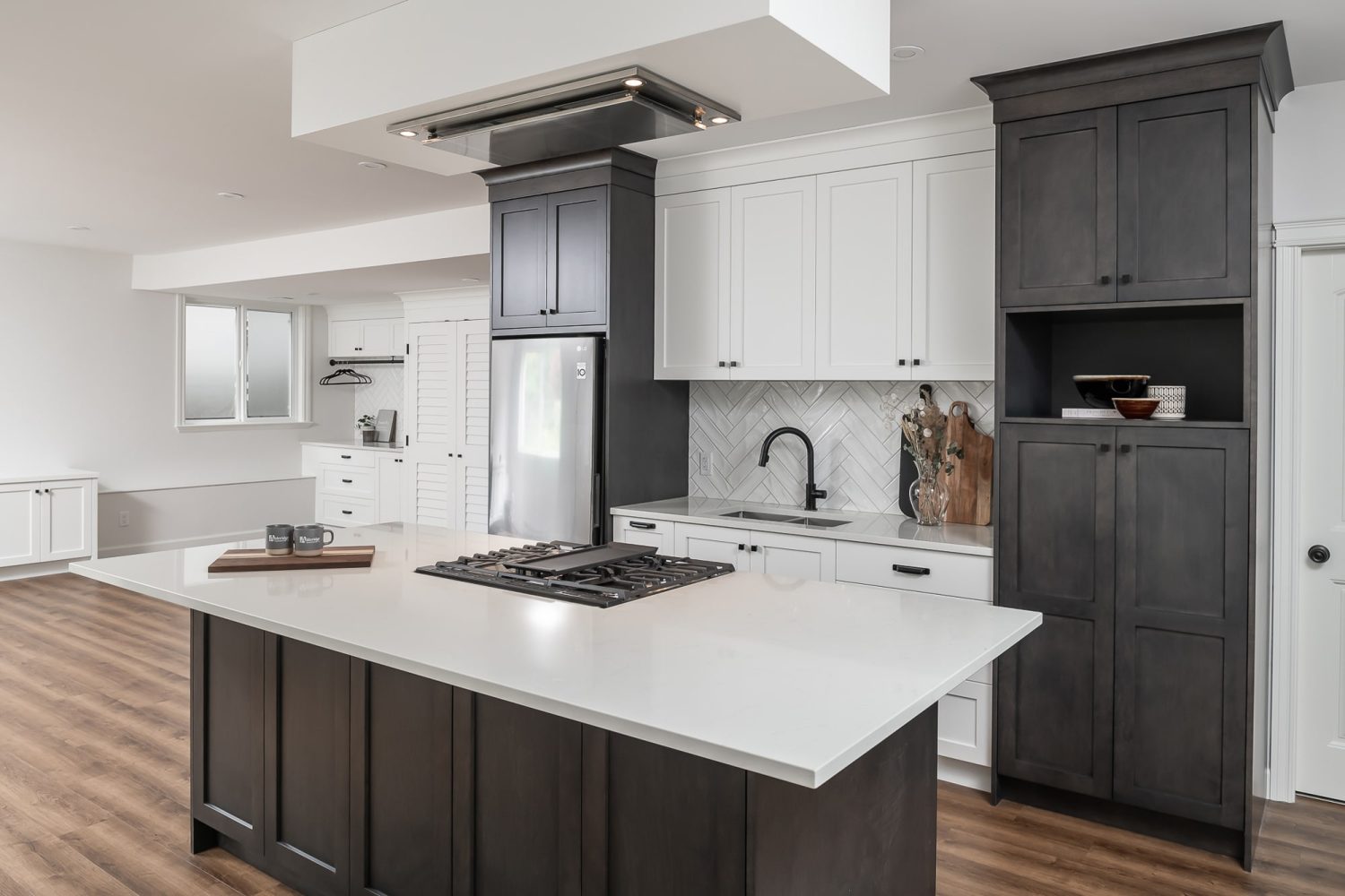 Two-tone custom kitchen by Alderidge Construction featuring white lower cabinetry paired with charcoal upper cabinets and a dramatic statement range hood