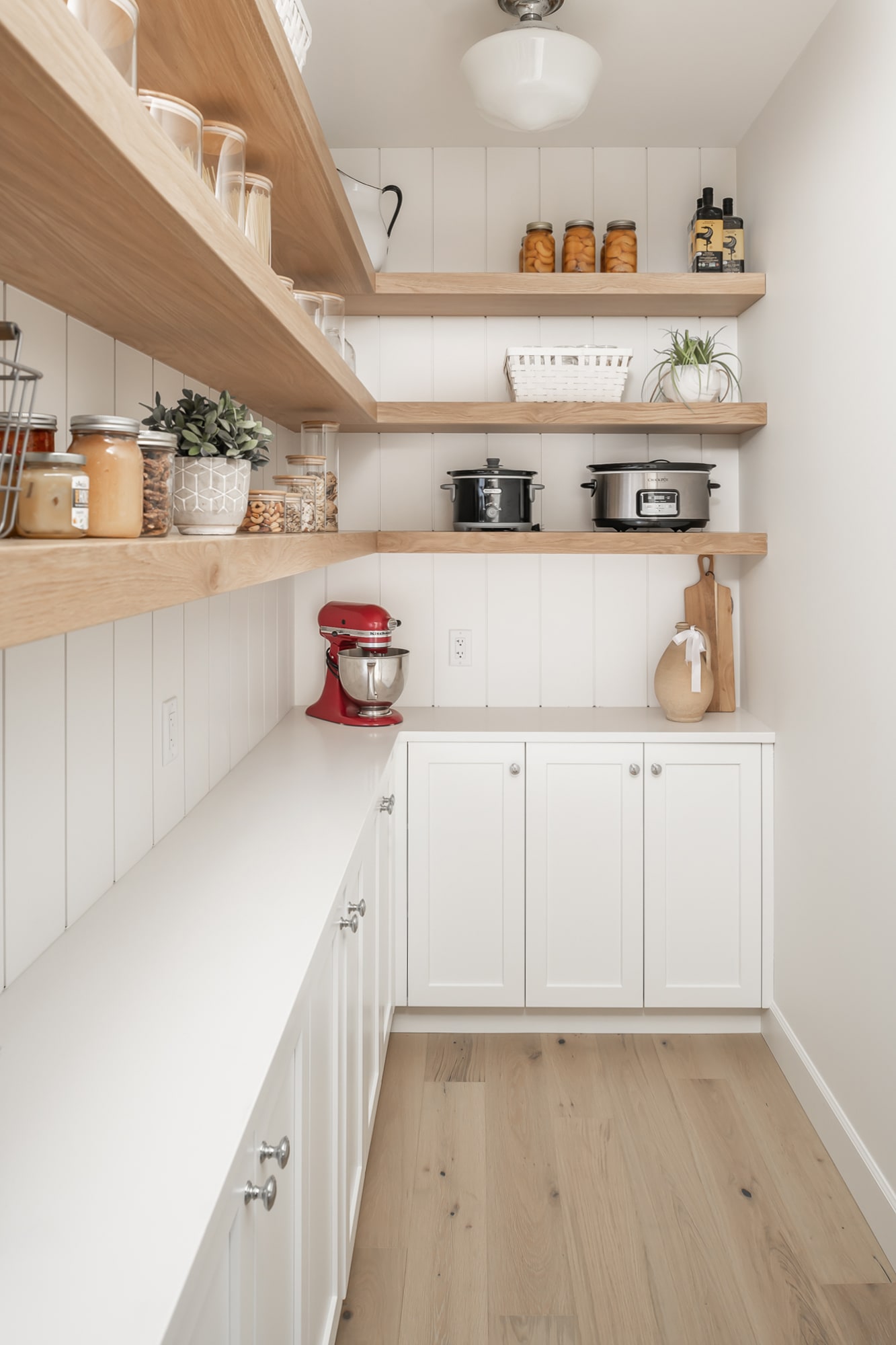 Custom walk-in pantry by Alderidge Construction featuring open natural wood floating shelves and white lower cabinetry for organized kitchen storage