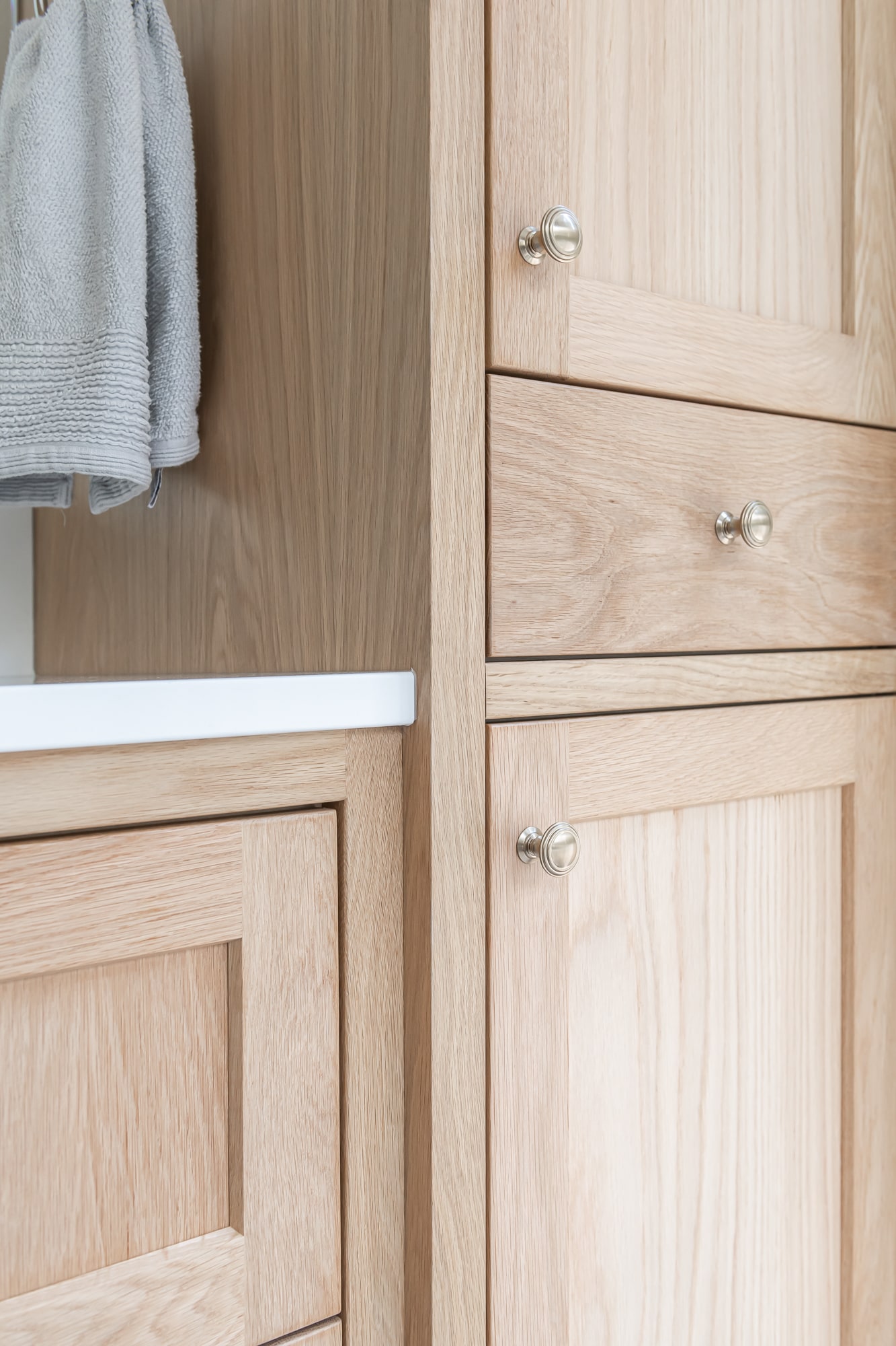 Custom light wood beadboard bathroom cabinet with round knob hardware by Alderidge Construction, showcasing fine craftsmanship in custom cabinetry millwork