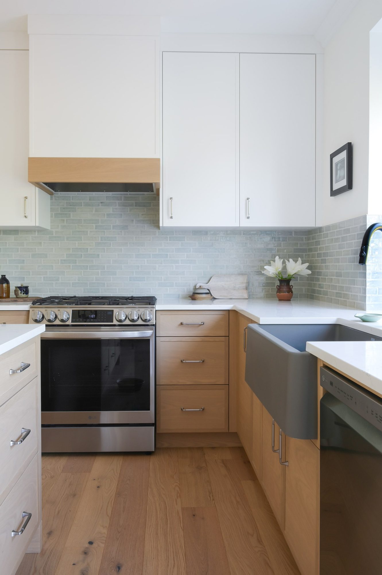Custom kitchen with natural wood upper cabinetry and integrated home office desk nook by Alderidge Construction, featuring stainless steel appliances and hardwood flooring
