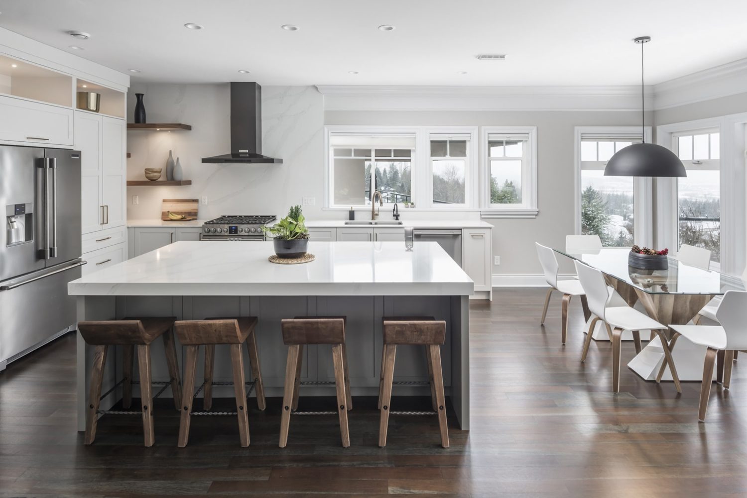 Spacious custom kitchen by Alderidge Construction with white perimeter cabinetry, dark contrasting island, leather bar stools, and professional range hood