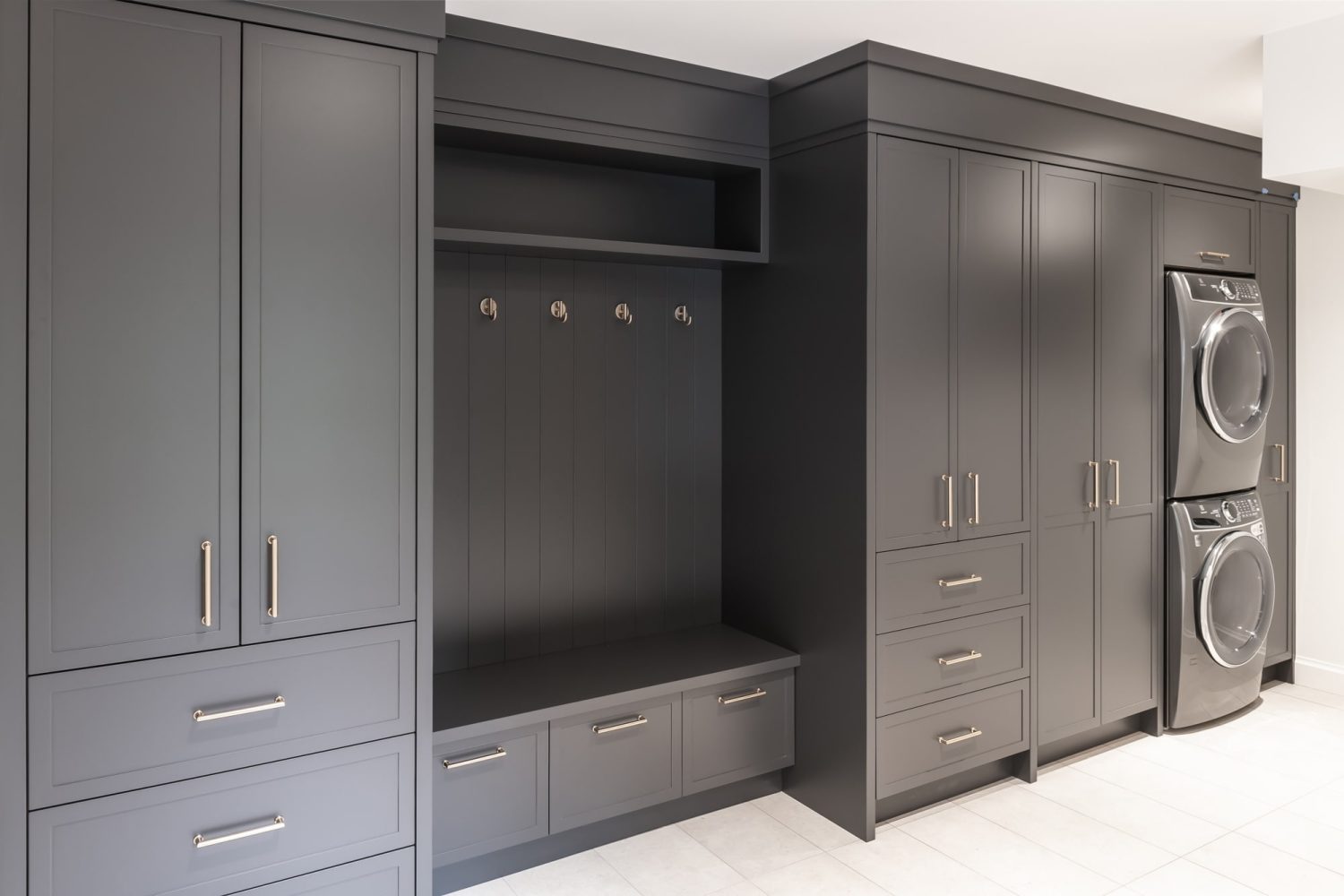 Dark charcoal mudroom with built-in locker cabinets and stacked gray washer and dryer