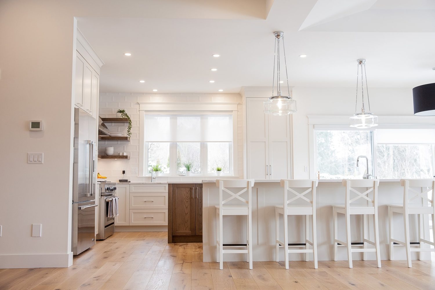 Custom kitchen cabinetry by Alderidge Construction featuring white upper cabinets, natural wood island with bar seating, and pendant lighting in an open concept layout