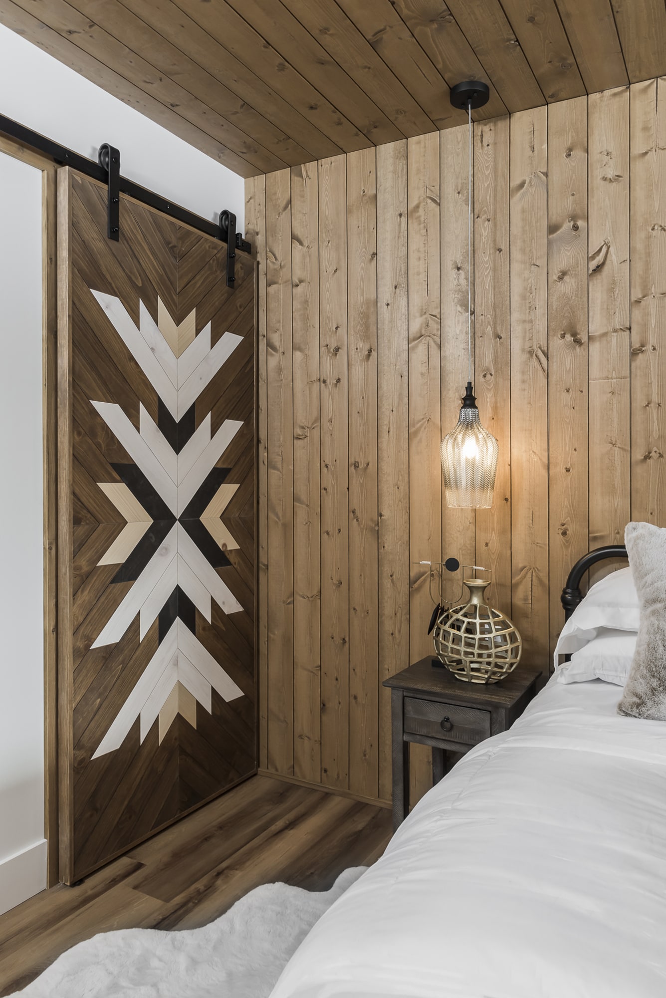 Custom geometric wood inlay barn door with shiplap wall paneling by Alderidge Construction, showcasing handcrafted cabinetry and millwork in a bedroom
