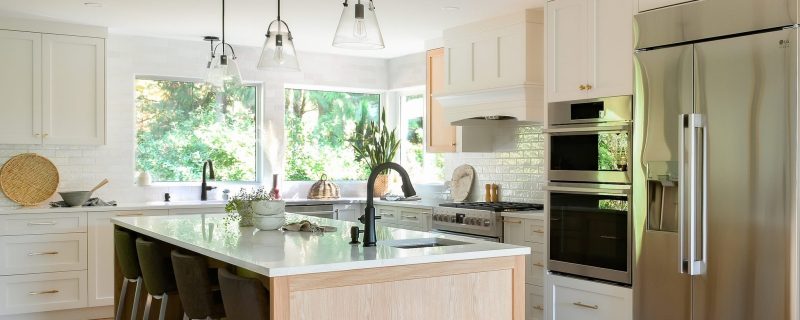 Renovated Shearwater kitchen with a white oak island, shaker cabinets, glass pendant lights and corner windows, by Alderidge Construction