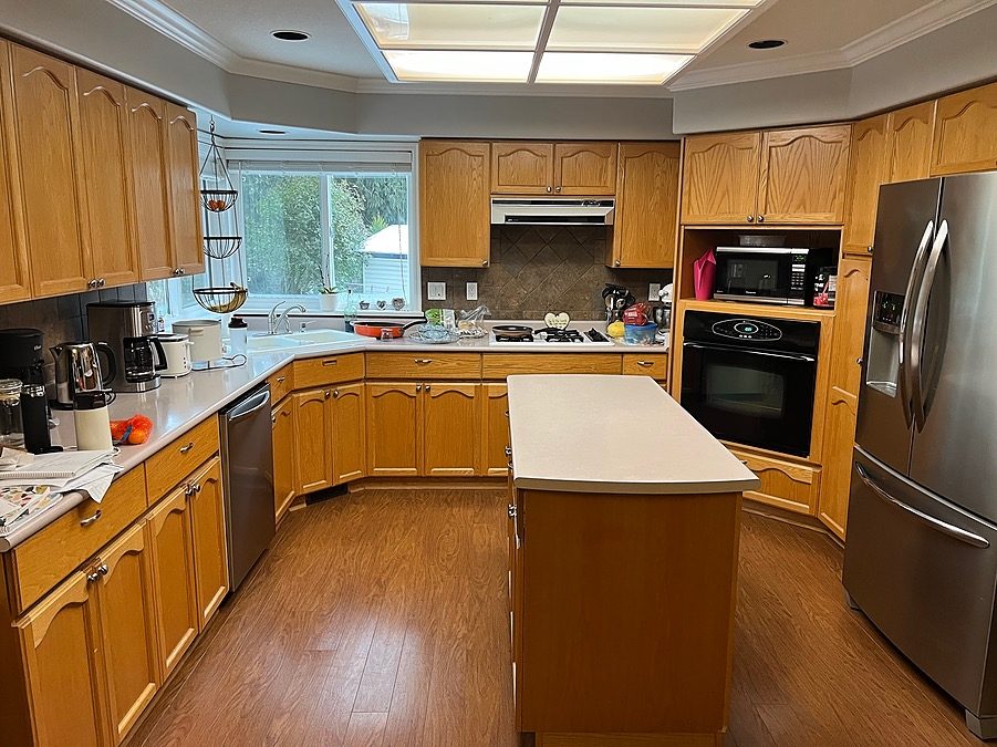 Shearwater kitchen before renovation, with oak cabinets, a small island and a fluorescent ceiling light panel