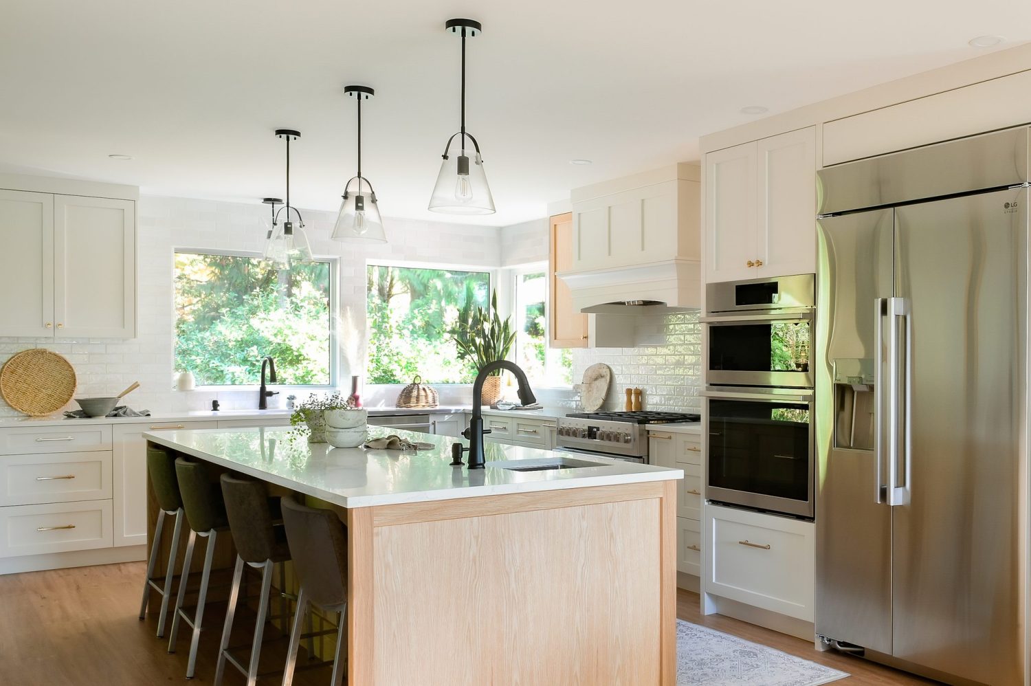 Shearwater kitchen after renovation, with a white oak island, white shaker cabinets, pendant lights and stainless appliances, by Alderidge Construction